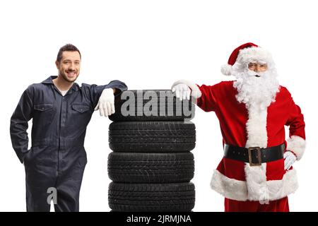 Auto mechanic and Santa Claus posing with a pile of tires isolated on ...