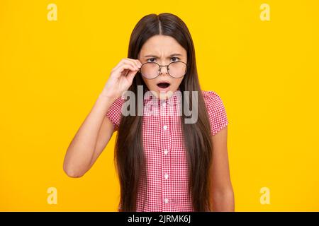 Shocked surprised teenager girl. Ophthalmologist tries on eyeglasses of teenager little girl, close-up. Treatment of childrens vision with glasses. Stock Photo