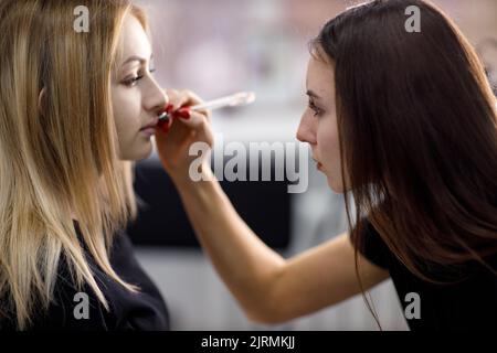 Cosmetologist applying drawing contour on lip before making lips microblading tattoo procedure. Stock Photo