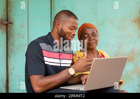 young black man talking to an old woman using a laptop Stock Photo