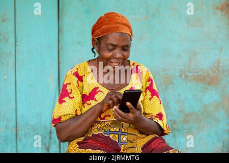 smiling elderly african woman using her smartphone Stock Photo