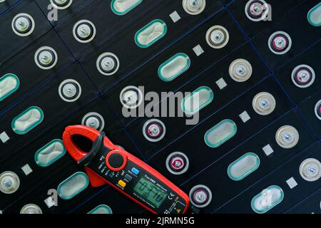 Electric vehicle lithium NMC battery with multimeter. Electric car battery manufacturing factory. Lithium-ion cell. Lithium NMC rechargeable battery. Stock Photo