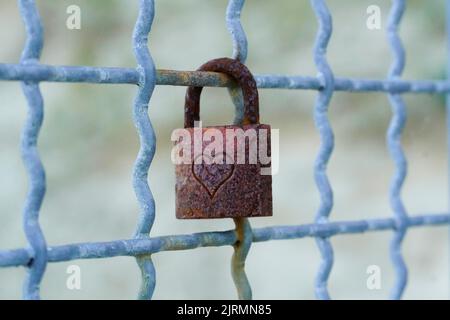 Old rusted love lock on a metal grille. Stock Photo