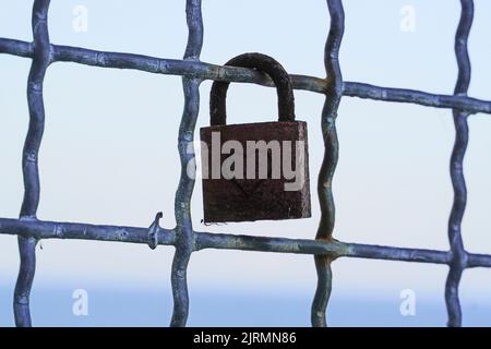 Old rusted love lock on a metal grille. Stock Photo