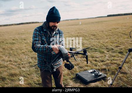 Man pilot checking quadcopter drone before aerial flight and filming Stock Photo