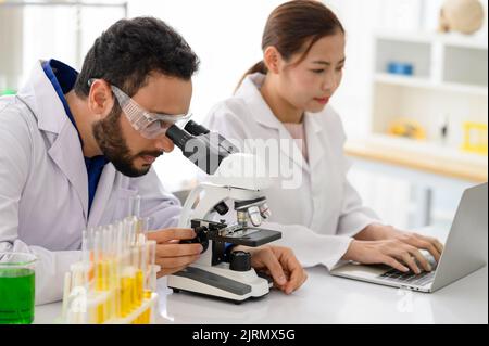 Chief research scientist adjusts specimen in petri dish and looks into microscope Stock Photo