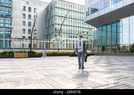 Handsome mature businessman with elegant suit walking in the business centre- Senior man with business suit portrait outdoors Stock Photo