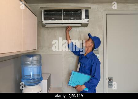 Young Asian technician checking conditioner in kitchen Stock Photo