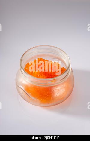 side view of closed glass jar with red caviar of pink salmon isolated on white background. Stock Photo