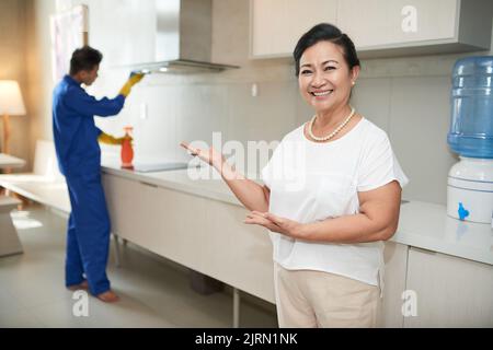 Happy Asian woman having plumber working in kitchen Stock Photo