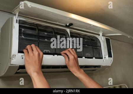 Hands of handyman repairing broken air conditioner Stock Photo