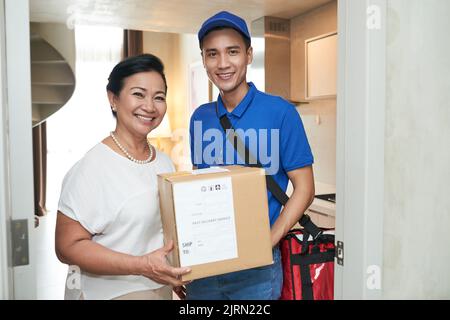 Happy senior woman and courier holding big box Stock Photo