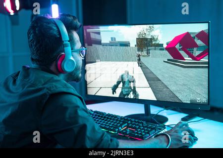 Young gamer with headset playing online video game on computer pc at home - concept of live streamer, online video gaming and competition. Stock Photo