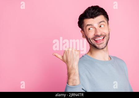 Profile portrait of positive nice person look indicate thumb finger empty space isolated on pink color background Stock Photo