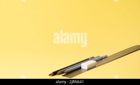 Simple pencils, ruler and eraser on a yellow background Stock Photo