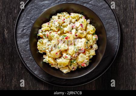 shout hallelujah potato salad with pickles, celery, eggs, jalapeno and mayonnaise dressing in black bowl, flat lay, close-up Stock Photo