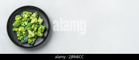 Broccoli in a black plate on a gray background. Stock Photo