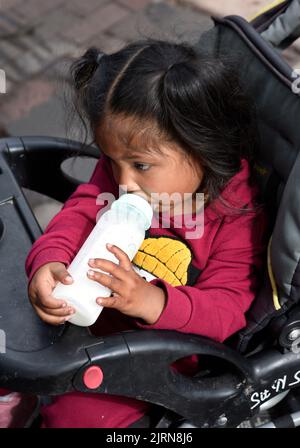 A Native American child in a baby carriage drinks from a baby bottle at the annual Santa Fe Indian Market art festival in Santa Fe, New Mexico. Stock Photo