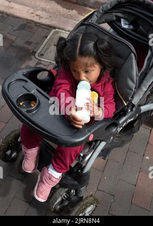 A Native American child in a baby carriage drinks from a baby bottle at the annual Santa Fe Indian Market art festival in Santa Fe, New Mexico. Stock Photo