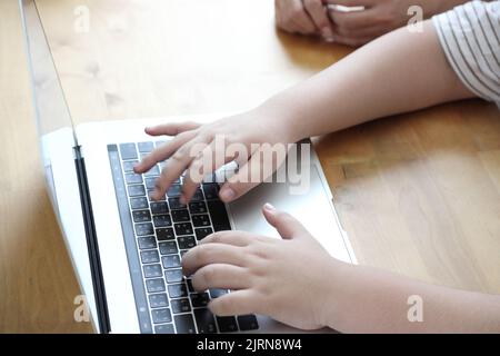 The close up shot of boy hands using laptop at home. Stock Photo