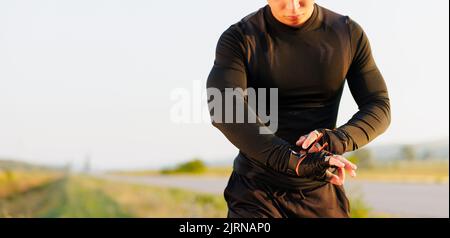 Athletic runner start training on fitness tracker or smart watch and looking forward on horizon. Trail running and active lifestyle concept. Stock Photo