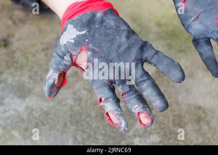 Defocus worn dirty and leaky gloves. Open palms of hands in worn workers gloves, protection against damage during operation, closeup on nature backgro Stock Photo