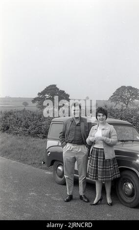 1950s, historical, a couple standing for a photo outside a small Austin A30 delivery van, parked on the grass verge on a country road,  England, UK. Stock Photo