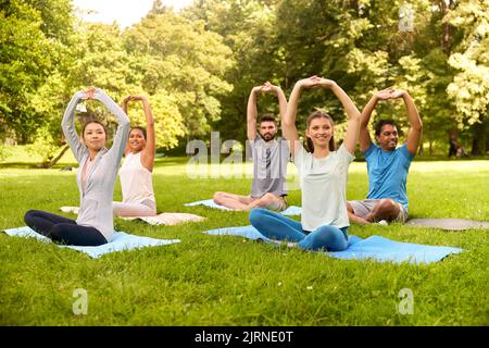 group of happy people doing yoga at summer park Stock Photo