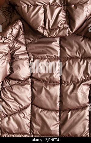 womens quilted bronze brown padded jacket as background, background of soft light fabric of a padded jacket, winter padded jacket Stock Photo