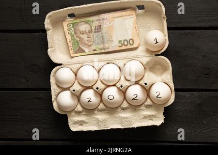 chicken eggs in boxes and the text 2022 on eggs and UAH 500 Ukrainian, happy new year 2022, chicken eggs on the table, 2021 and 2022, income in the ne Stock Photo