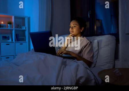 woman with laptop in bed at home at night Stock Photo