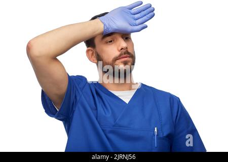 tired doctor or male nurse in blue uniform Stock Photo