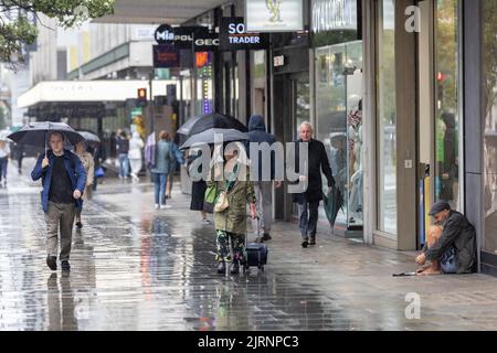 Commuters and tourists brave the torrential summer rain showers on Oxford Street in London after a mini-heatwave and weeks of dry weather over the UK. Stock Photo