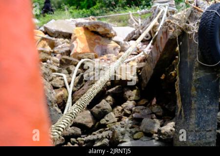 Mooring rope with a knotted end is tied around a cement pole on the pier. Nautical mooring rope. The concept of mooring and water transportation Stock Photo