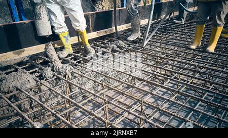 Construction workers are pouring concrete to formwork Stock Photo