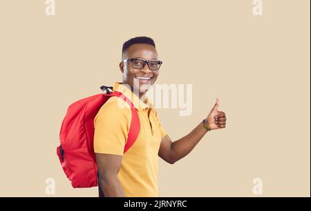 Happy African American university student with backpack giving thumbs up and smiling Stock Photo