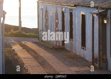 Dunure, Ayrshire, Scotland, UK. Row of cottages on coast with the evening sun setting. Stock Photo