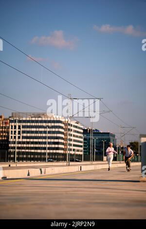 Two teenagers are running and skating skateboard, having fun in the urban exterior. Stock Photo