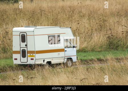 Vauxhall Bedford Rascal 1991 Nipper, 3 Berth, Overcab bed Campervan driving through parched summer countryside Stock Photo