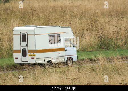 Vauxhall Bedford Rascal 1991 Nipper, 3 Berth, Overcab bed Campervan driving through parched summer countryside Stock Photo