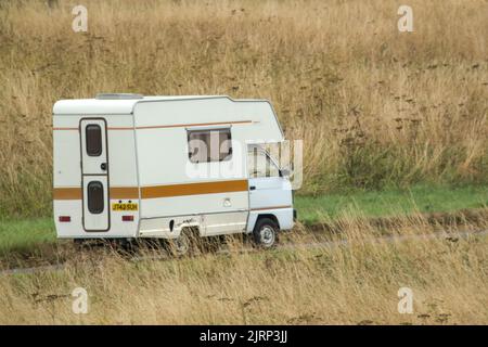 Vauxhall Bedford Rascal 1991 Nipper, 3 Berth, Overcab bed Campervan driving through parched summer countryside Stock Photo