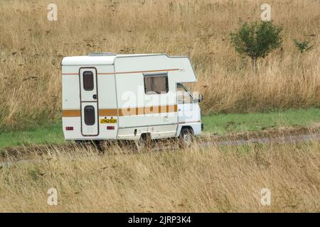 Vauxhall Bedford Rascal 1991 Nipper, 3 Berth, Overcab bed Campervan driving through parched summer countryside Stock Photo