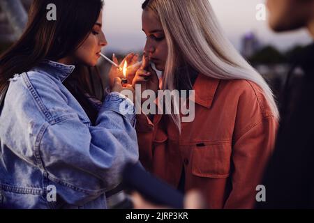 Two rebellious teenage girls lightning cigarettes and smoke. Teenagers smoking cigarettes Stock Photo