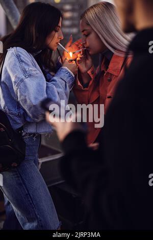 Two rebellious teenage girls lightning cigarettes and smoke. Teenagers smoking cigarettes Stock Photo