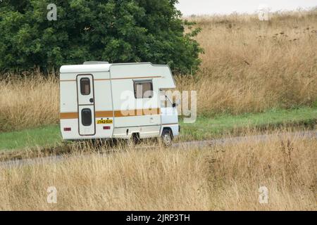 Vauxhall Bedford Rascal 1991 Nipper, 3 Berth, Overcab bed Campervan driving through parched summer countryside Stock Photo