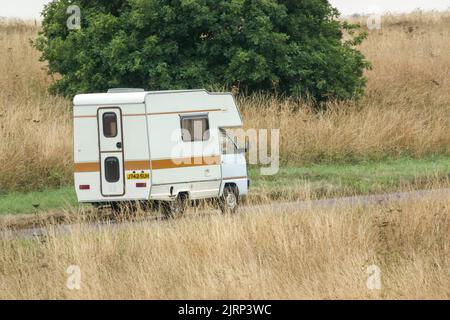 Vauxhall Bedford Rascal 1991 Nipper, 3 Berth, Overcab bed Campervan driving through parched summer countryside Stock Photo