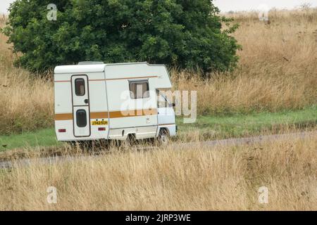 Vauxhall Bedford Rascal 1991 Nipper, 3 Berth, Overcab bed Campervan driving through parched summer countryside Stock Photo