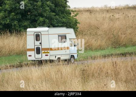 Vauxhall Bedford Rascal 1991 Nipper, 3 Berth, Overcab bed Campervan driving through parched summer countryside Stock Photo