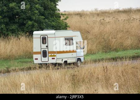 Vauxhall Bedford Rascal 1991 Nipper, 3 Berth, Overcab bed Campervan driving through parched summer countryside Stock Photo