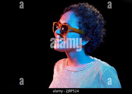 african woman in sunglasses over neon lights Stock Photo